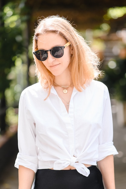 Girl in sunglasses walks on a blurred background