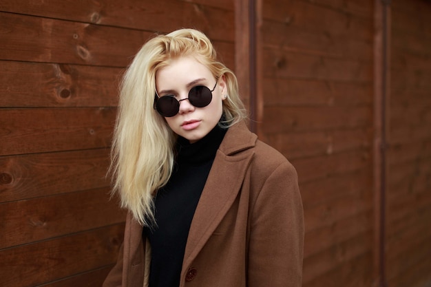 Girl in sunglasses on the wooden background.