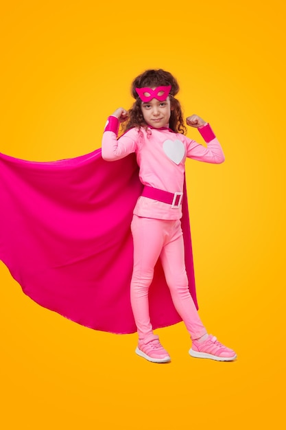 Девушка в костюме супергероя показывает мускулы