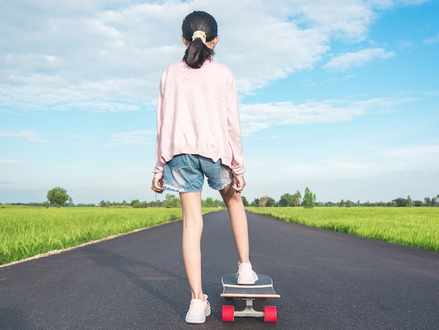 田舎の道路でサーフスケートの女の子