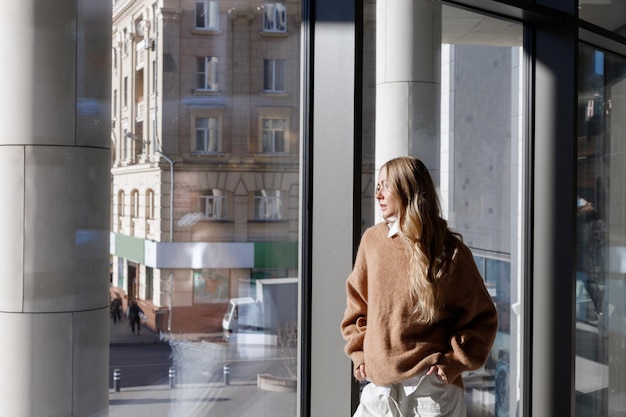 Girl in a sweater by the window overlooking the city