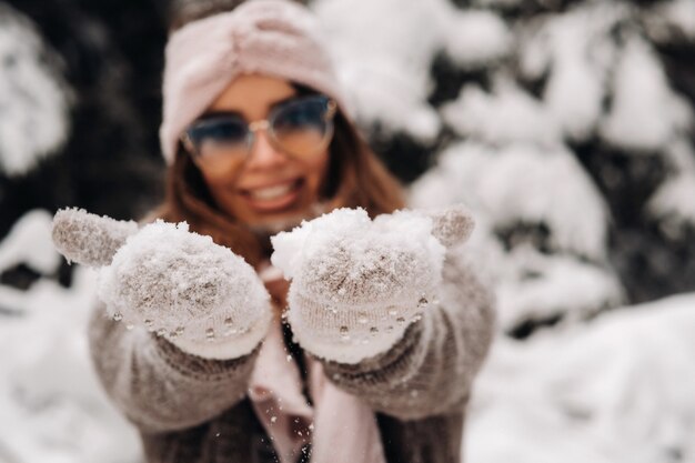 A girl in a sweater and glasses in winter in a snow-covered forest