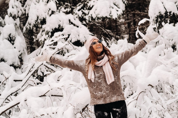 A girl in a sweater and glasses in winter in a snowcovered forest