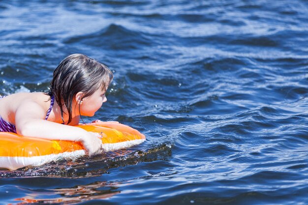 Girl swims with inflatable mattress on the water