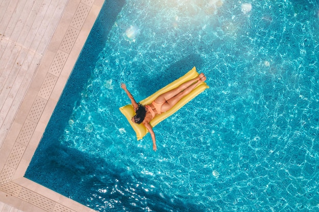 Ragazza in costume da bagno che si abbronza in piscina