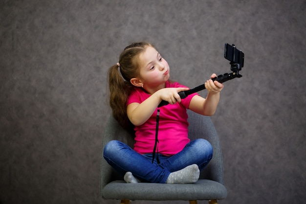 Girl in A T-shirt takes a selfie on her phone and poses