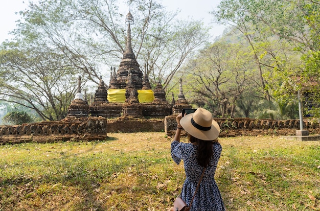 Girl take a photo of ancient pagoda in Thailand 