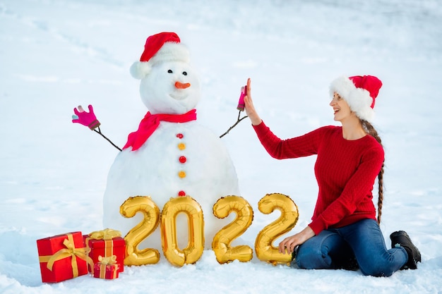 A girl takes five to Decorated Snowman with figures of the upcoming new year and gifts at its base