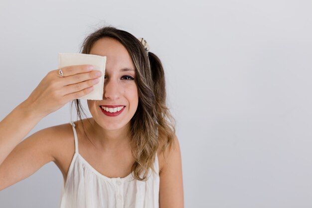 girl takes off her makeup with a cloth pad with eyes open