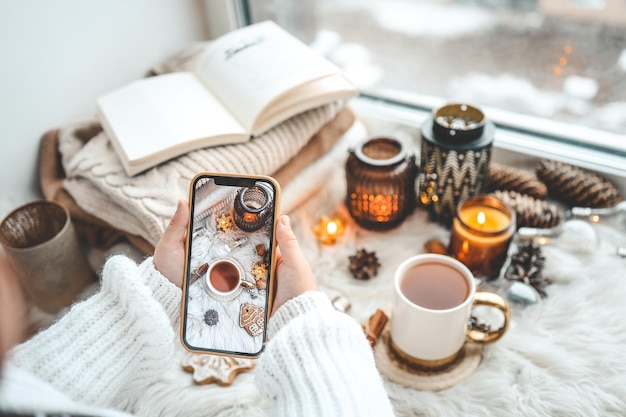 The girl takes a photo of the Christmas decor the phone is in her hands