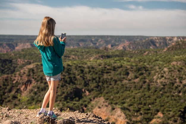 写真 女の子が携帯電話で峡谷の写真を撮る