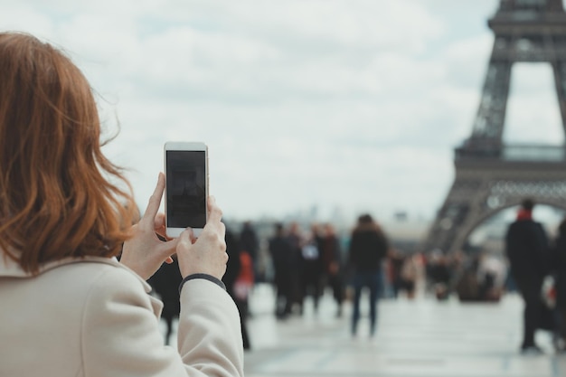 女の子がスマートフォンでエッフェル塔の写真を撮る