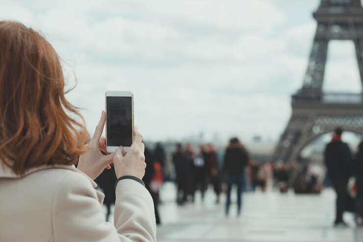 Photo girl takes pictures of a eiffel tower on a smartphone