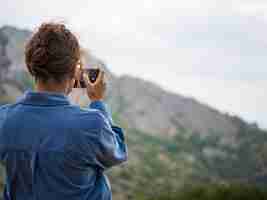 Photo girl takes pictures of mountain landscape on her phone