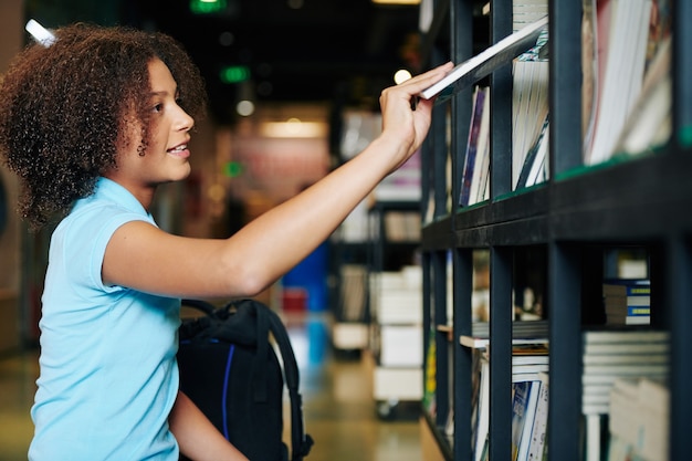 Девушка берет книгу в книжном магазине