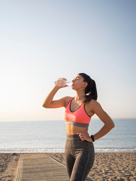 Girl taking a break during the race to hydrate during exercise on the beach healthy lifestyle