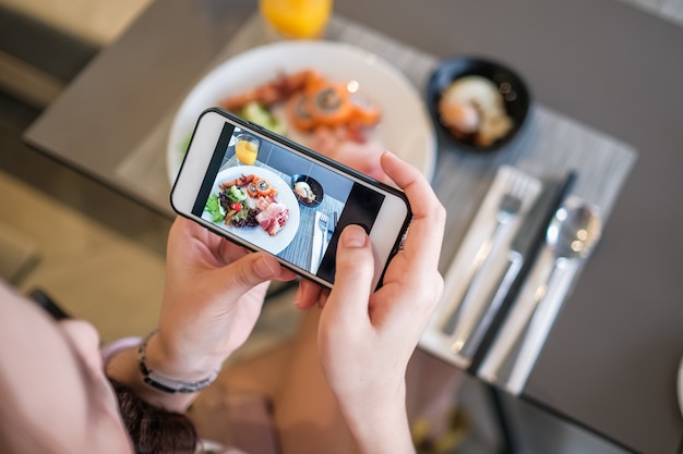 携帯電話のカメラで食べ物の写真を取っている女の子