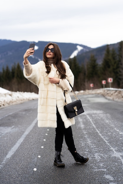 Girl taking photo of her self on smartphone on winter mountains