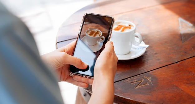 写真 一杯のコーヒーの写真を撮っている女の子