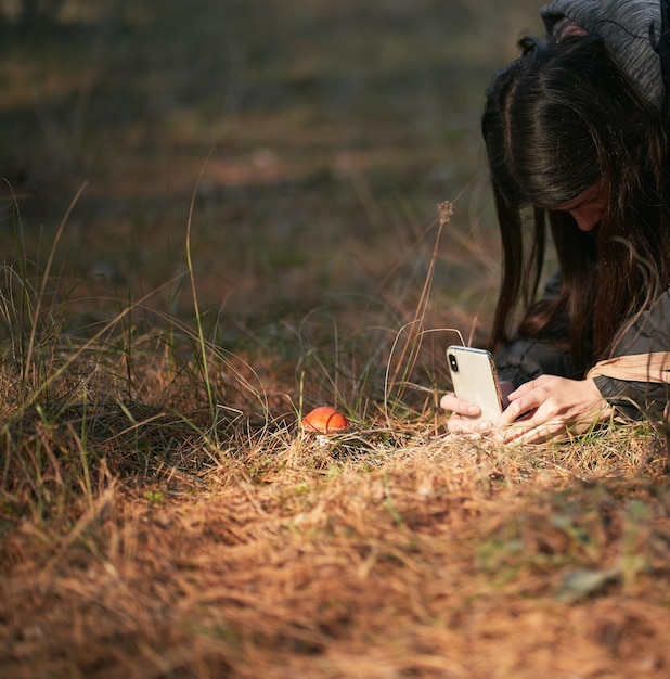 Photo girl taking picture with smartphone of fly agaric closeup in autumn forest mushroom spotting