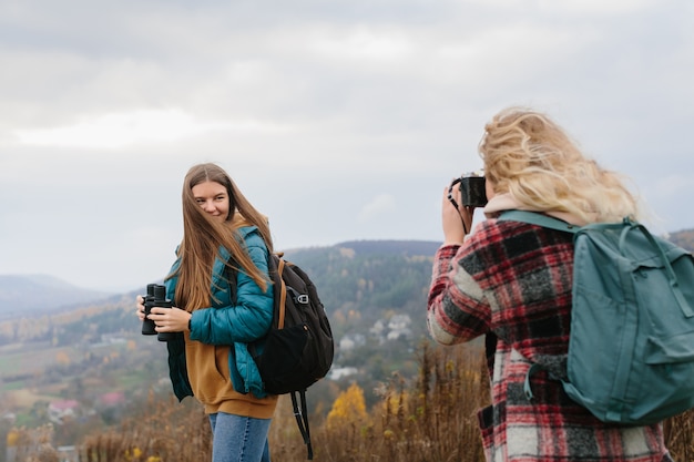 Girl taking pictures of friend in mountains while hiking