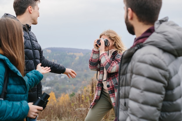 ハイキング中に山で友達の写真を撮る女の子