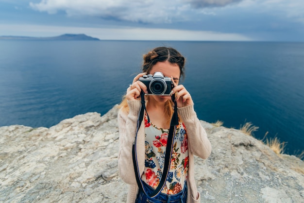Девушка фотографируя outdoors на ретро камере на летних каникулах
