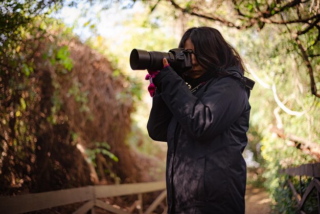 Girl taking pictures with dslr camera reflex in natural reserve Argentina