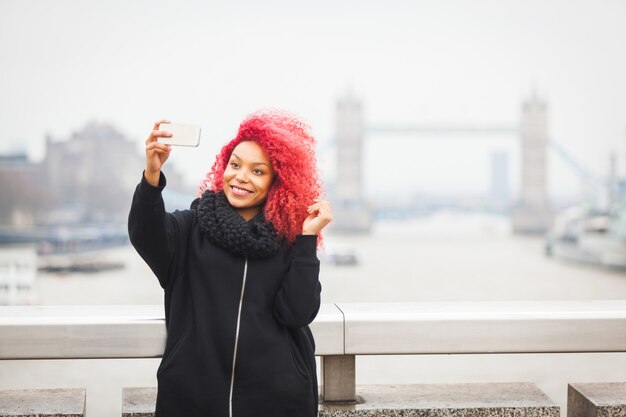 Girl taking selfie in London with Tower Bridge 