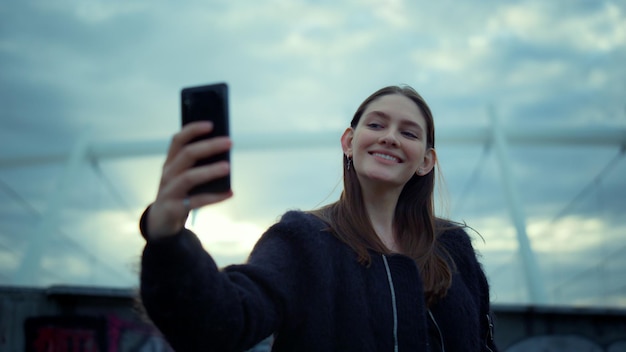 Girl taking selfie on smartphone in modern city Happy woman using mobile phone