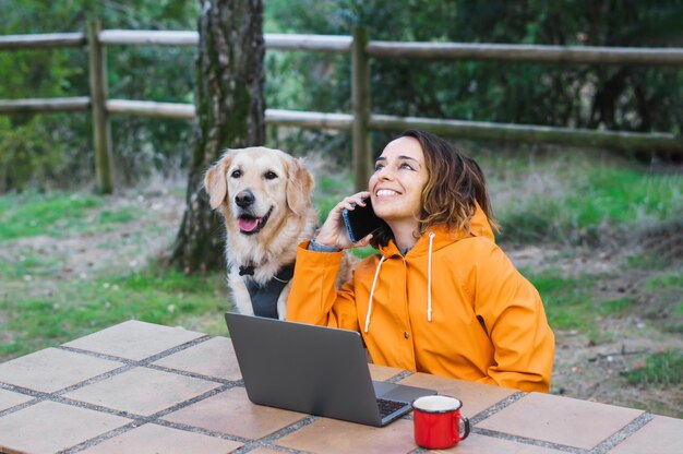 コンピューターと犬の横にある電話で話している女の子