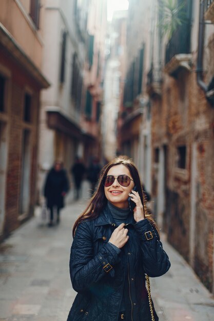 電話で話して、イタリアのヴェネツィアで写真を撮っている少女