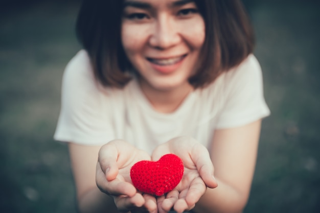 写真 十代の少女は、寄付医療ヘルスケアの概念を与えるために手に赤いハートと笑顔します。