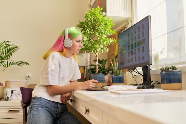 Girl teenager artist in headphones drawing on computer using graphics tablet