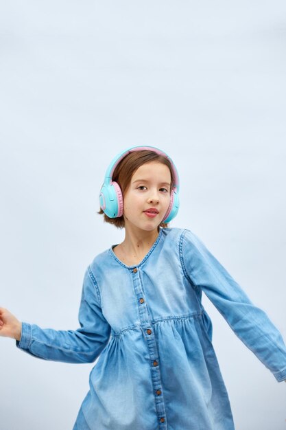 Girl teenager in casual denim dress listening to music in headphones