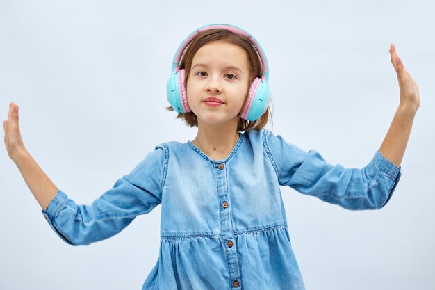 Girl teenager in casual denim dress listening to music in headphones