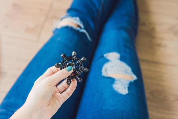 Girl teenager in holey jeans holds in hands and plays with spinner