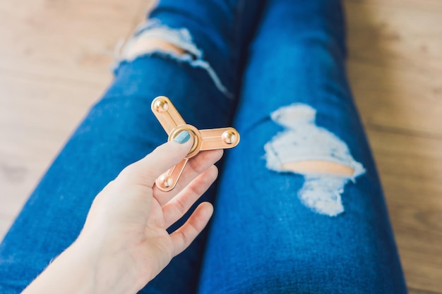 Girl teenager in holey jeans holds in hands and plays with spinner