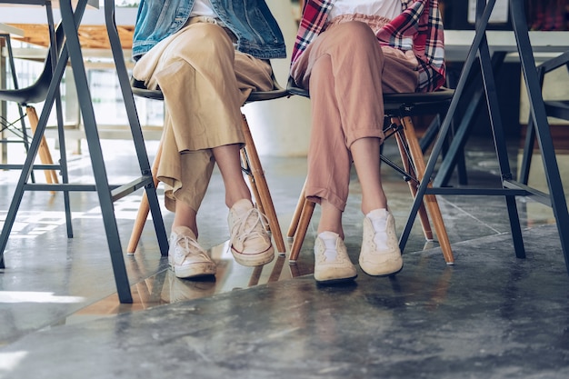 Girl teenager legs wearing sneakers sitting talking together