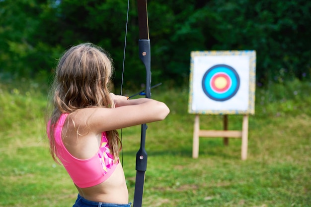 Foto adolescente della ragazza con la cocca dell'arco e mira a mirare