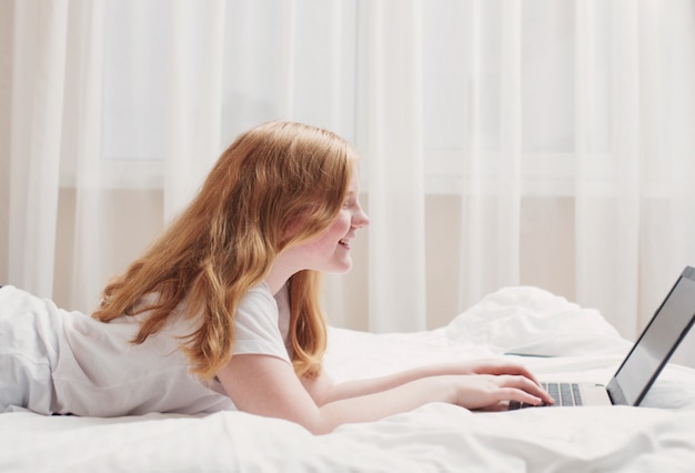 Girl teenager with laptop in bed