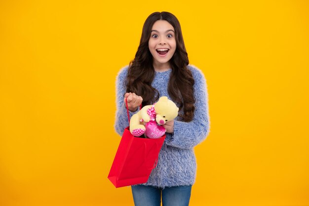 Girl teenager with shopping bags isolated on yellow backgound shopping and sale concept happy teenager positive and smiling emotions of teen girl