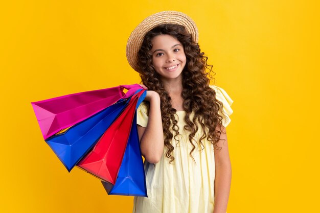 Girl teenager with shopping bags isolated on yellow backgound Shopping and sale concept Happy teenager positive and smiling emotions of teen girl