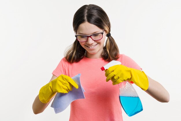 Girl teenager in yellow gloves with rag and spray detergent.