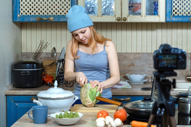 写真 10代の少女の若い食べ物のブロガーが食べ物を準備し、レシピをカメラに書き込みます。