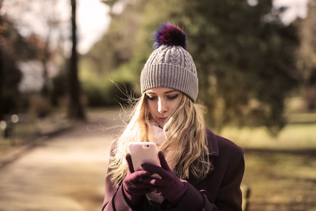 Ragazza che manda un sms sul suo smartphone mentre camminando