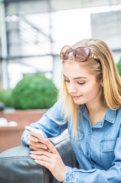 Girl texting on the smart phone in a shpping mall sitting in internet free zone.