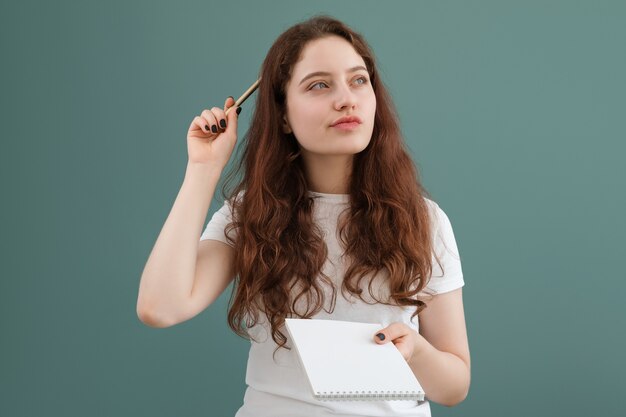 Girl thinks what to write in her notebook