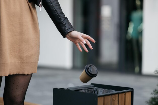 The girl throws a paper cup in the trash paper cup disposal\
cardboard and trash