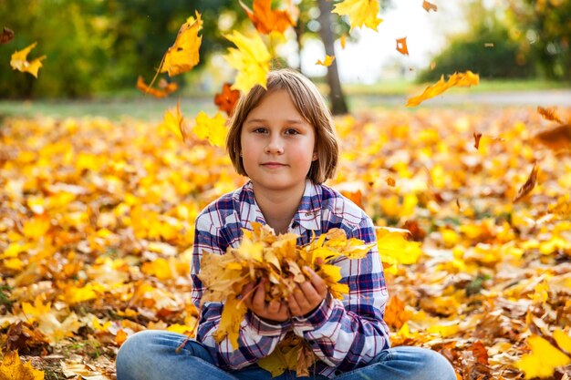 Girl throws yellow autumn leaves into the air